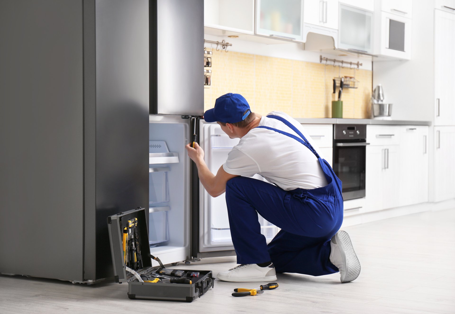a technician repairing a refrigerator - Arlington Appliance Repair Experts