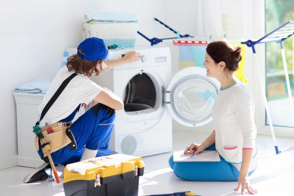 a technician repairing a washer while woman is watching - appliance repair service Arlington