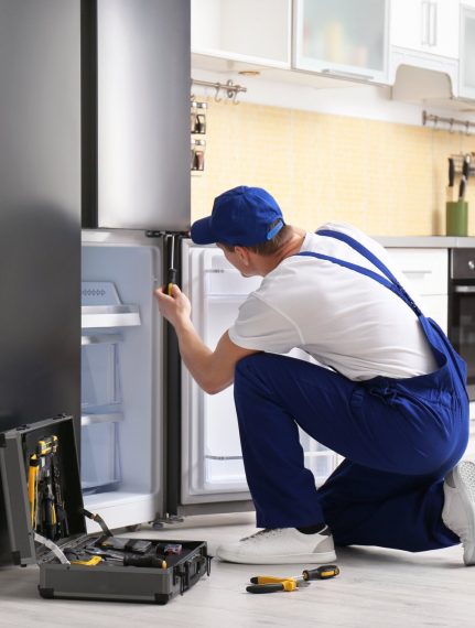 a technician repairing a refrigerator - Arlington Appliance Repair Experts